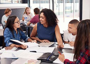 A group of students circled around a table working on a paper